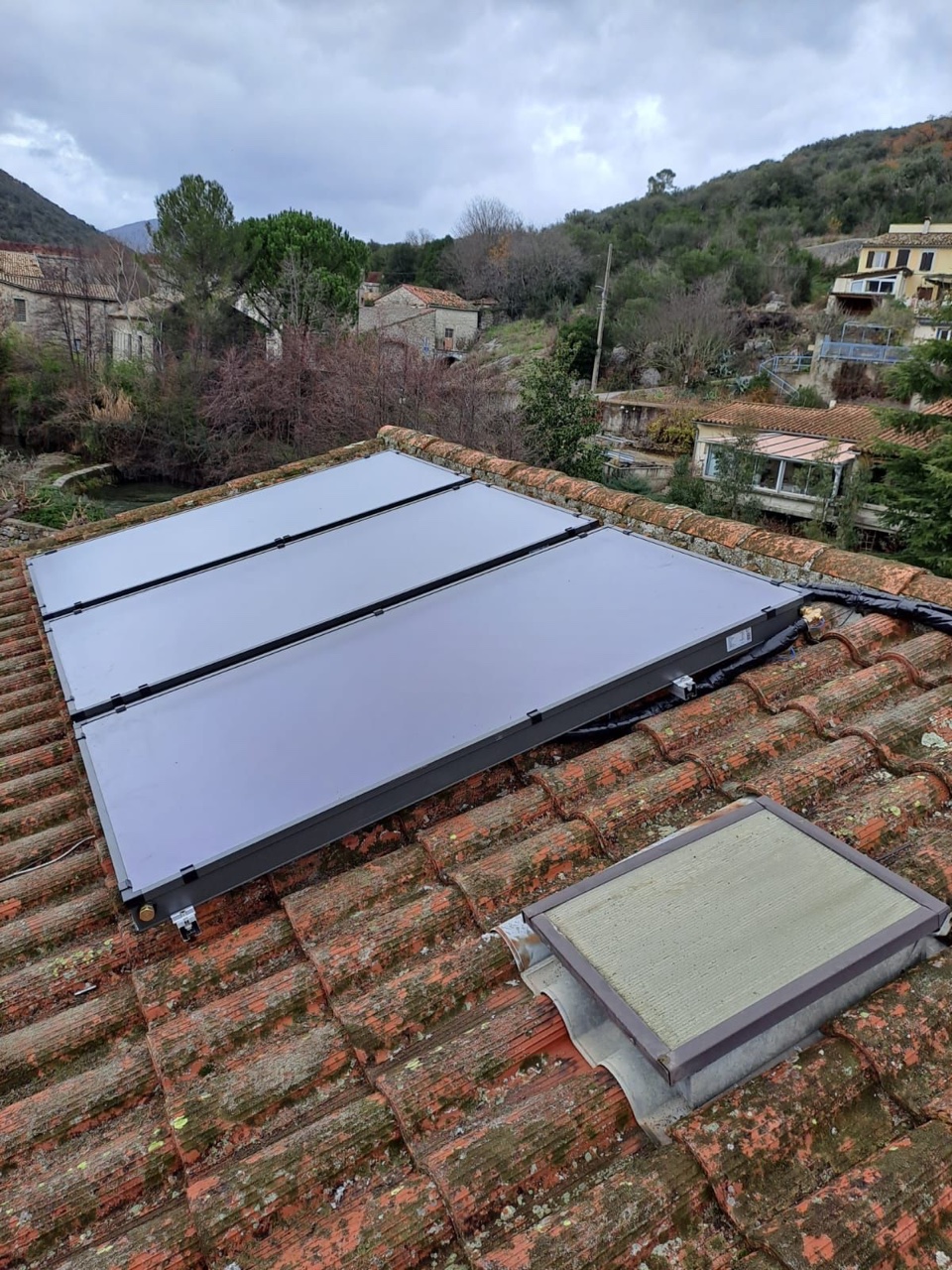 Capteurs solaires thermiques plans installés par AMBE Énergies sur le toit en tuiles canal d'une maison de village du Sud