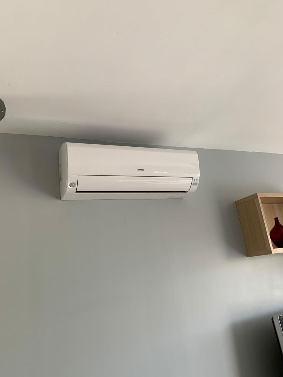 Unité intérieure murale de climatisation Hitachi sur un mur gris bleuté d'une pièce à vivre
