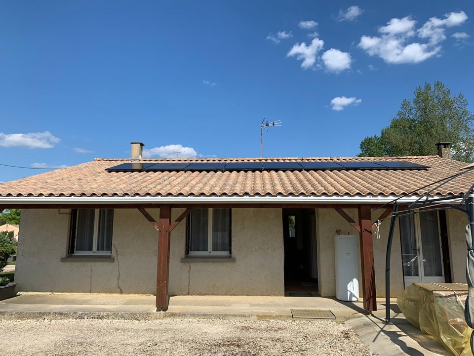 Rangée de panneaux photovoltaïques noirs sur toit en tuiles canal d'une maison de plain-pied