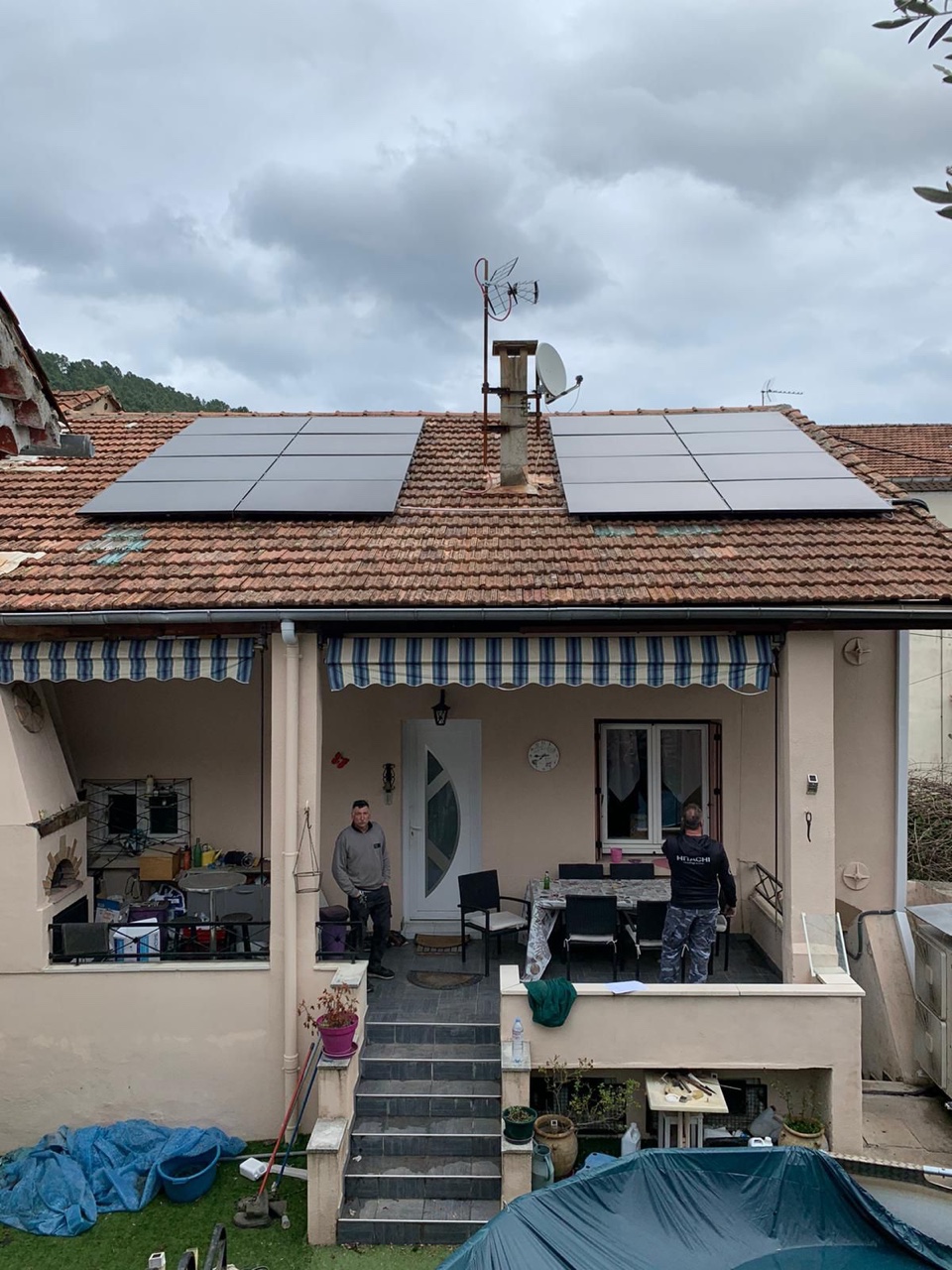 Deux groupes de panneaux photovoltaïques sur toit en tuiles, deux personnes sur la terrasse couverte