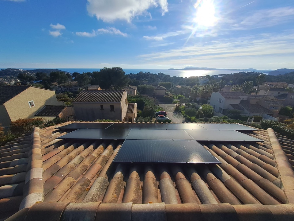 Panneaux photovoltaïques noirs sur un toit en tuiles canal d'une villa avec vue sur la mer