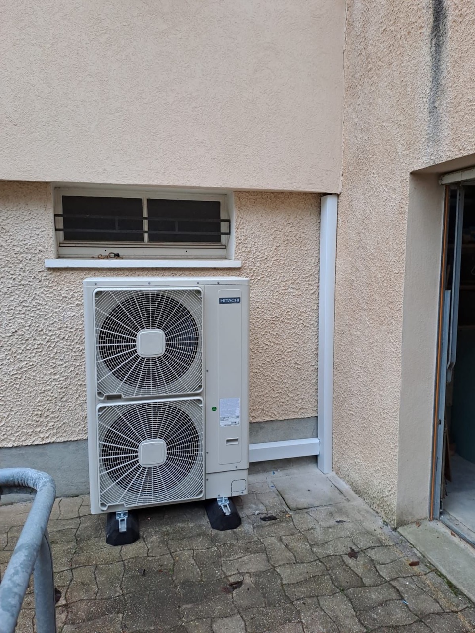 Unité extérieure de pompe à chaleur Hitachi à deux ventilateurs posée sur plots antivibratiles